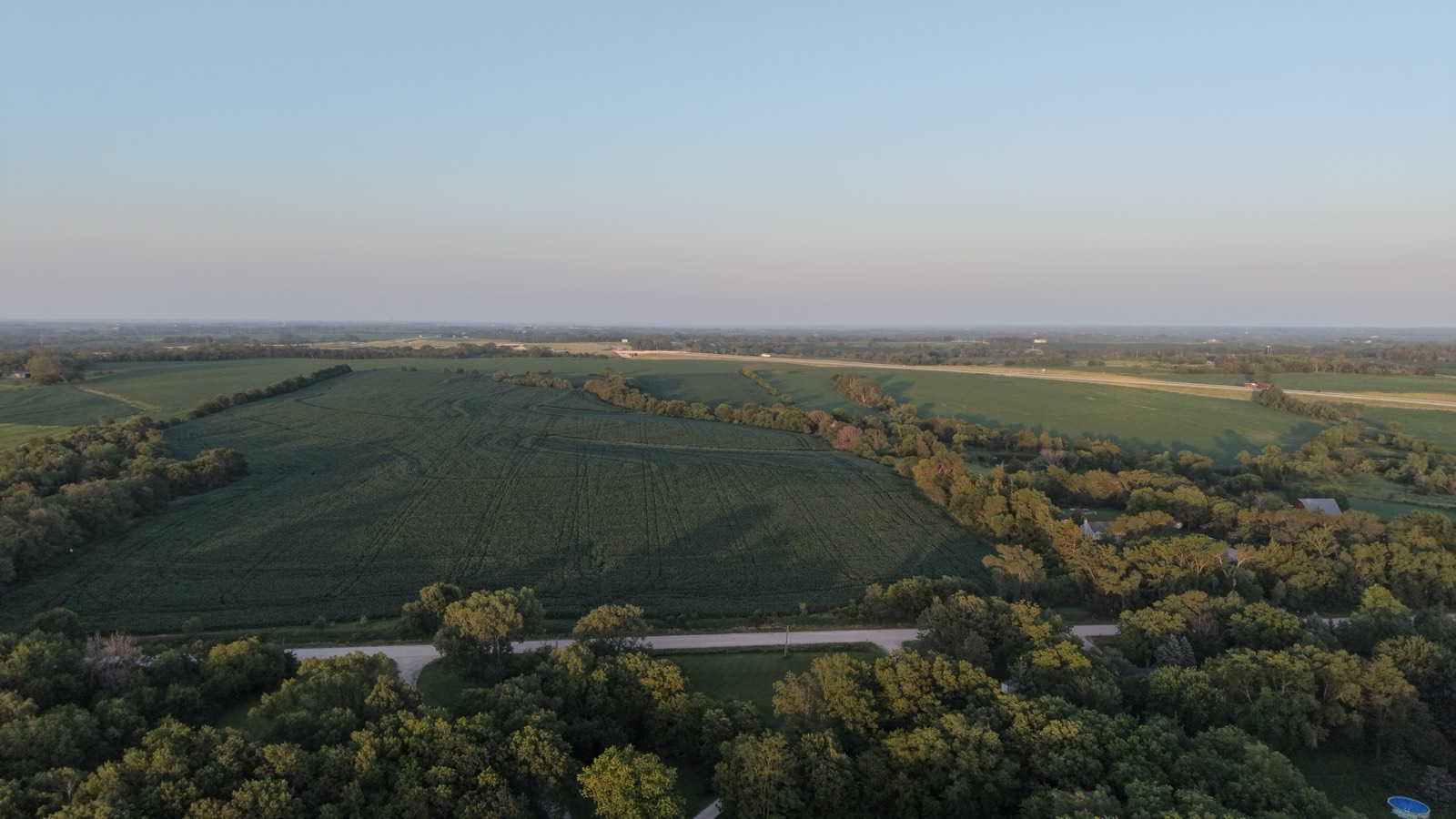 Golden-hour aerial over patchwork farmland and crop fields on the plains