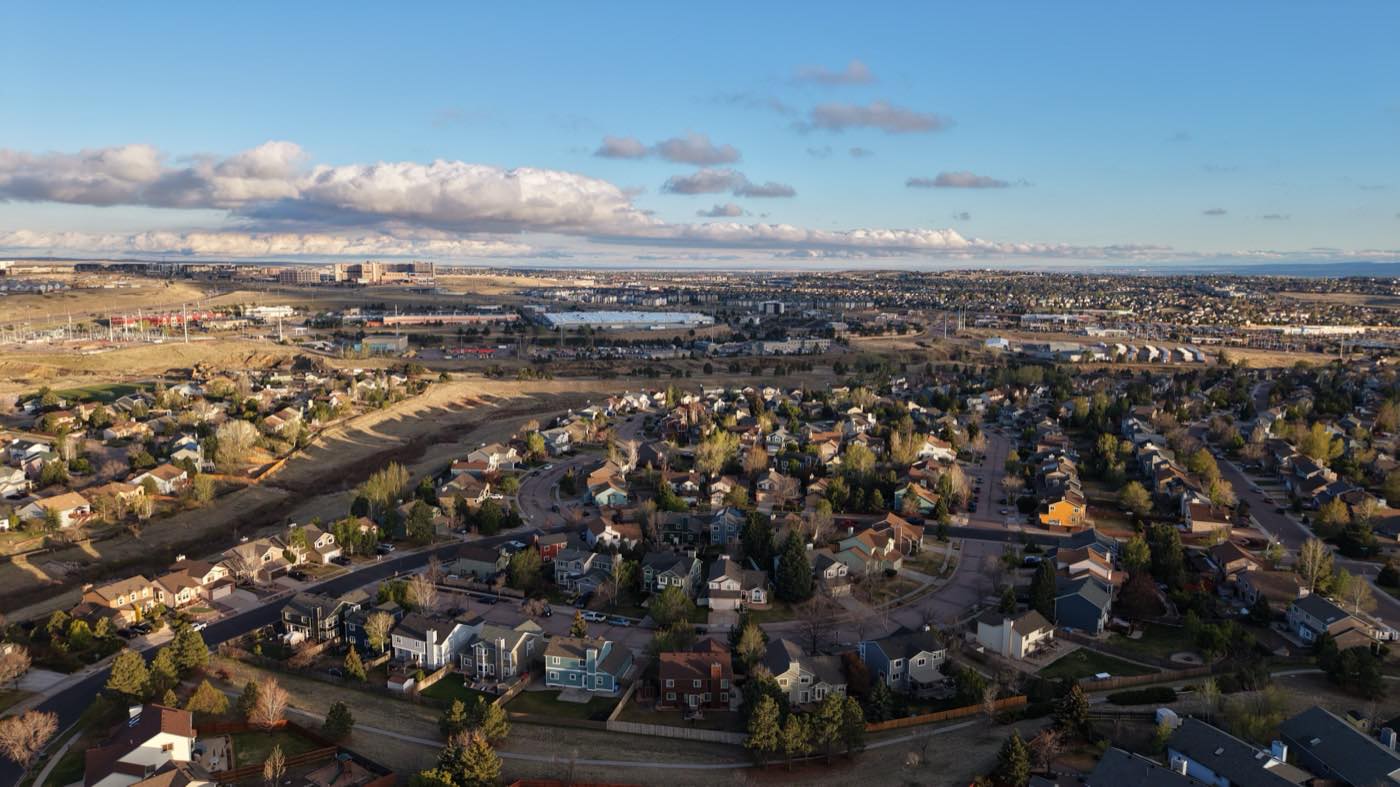 Daytime aerial of a residential neighborhood with mountains beyond