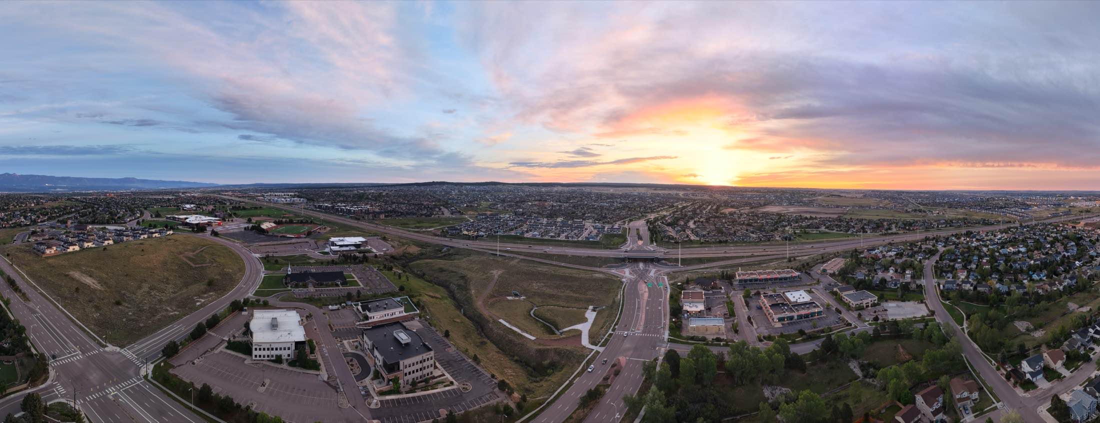 Wide panoramic aerial of a town at sunset with sweeping clouds