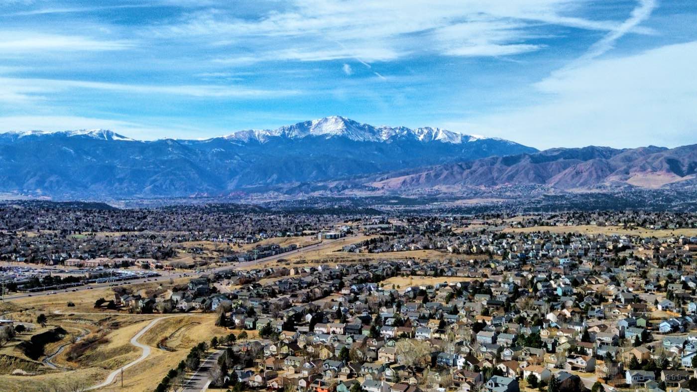 Aerial overlook of a city with Pikes Peak on the horizon